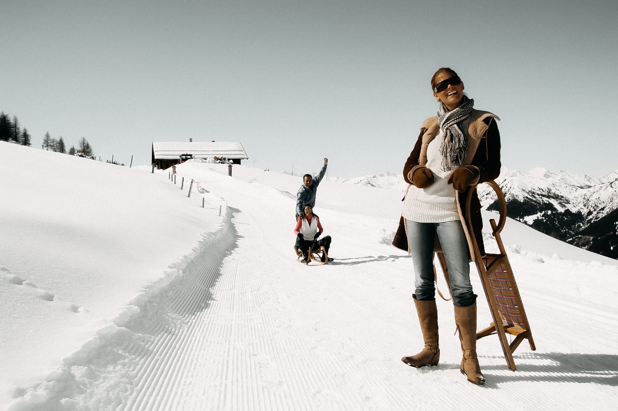 Drei Personen rodeln durch den Schnee.
